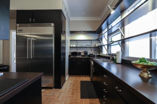 a kitchen with a stainless steel refrigerator and black cabinets at 4BR The Montrose Caliber, Grandeur Home, Near All in Houston