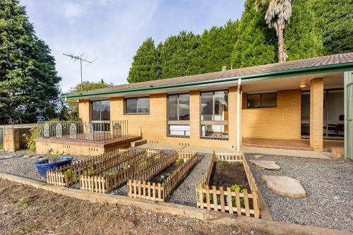a house with a row of plants in front of it at Serene Farmhouse with Lake Views in Burrawang