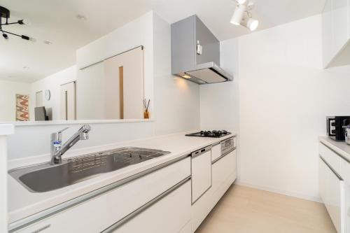 a kitchen with white cabinets and a sink at Megumi in Osaka