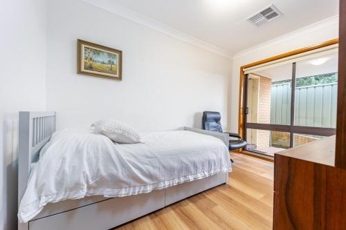 a white bedroom with a bed and a window at Serene Farmhouse with Lake Views in Burrawang