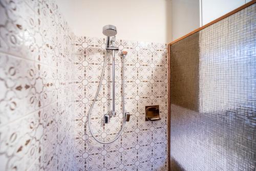 a shower in a bathroom with a tiled wall at Serene Farmhouse with Lake Views in Burrawang