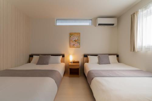 two beds in a room with white walls at Megumi in Osaka