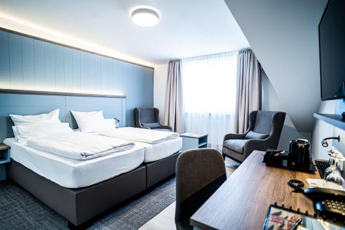 a hotel room with a bed and two chairs and a table at Hotel Seeschwalbe in Cuxhaven