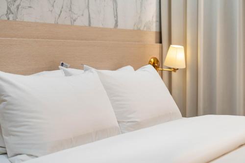 a white bed with white pillows and a lamp at Benikea Hotel Bizinn in Wonju