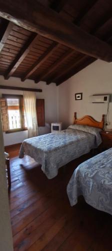 una camera da letto con due letti e pavimento in legno di Casa rural El Corralón a Hinojal