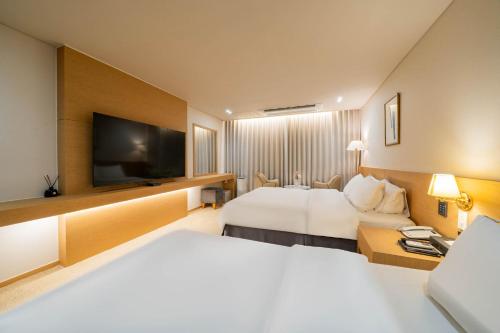 a hotel room with two beds and a flat screen tv at Benikea Hotel Bizinn in Wonju