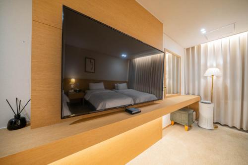 a bedroom with a large television on a wall at Benikea Hotel Bizinn in Wonju