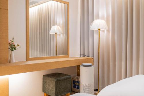 a bedroom with two lamps and a mirror at Benikea Hotel Bizinn in Wonju