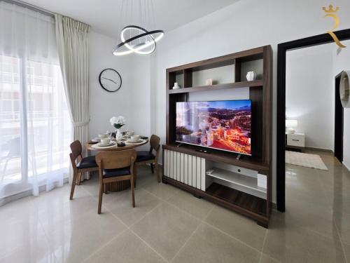 a dining room with a television and a table with chairs at Balcony 1BR Retreat - Stylish Dining Escape in Abu Dhabi