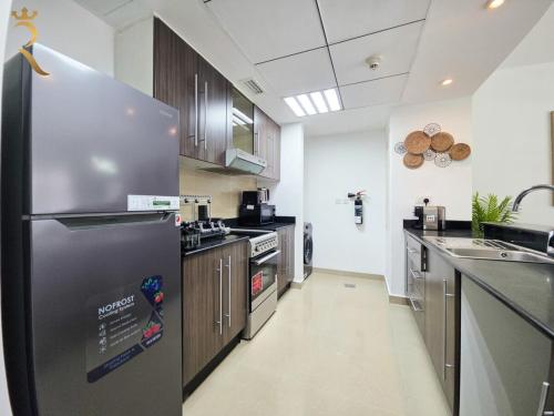 a kitchen with a stainless steel refrigerator and cabinets at Balcony 1BR Retreat - Stylish Dining Escape in Abu Dhabi