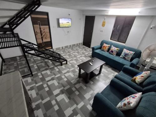a living room with two blue couches and a table at Tulip - Duplex on the Terrace in Guwahati
