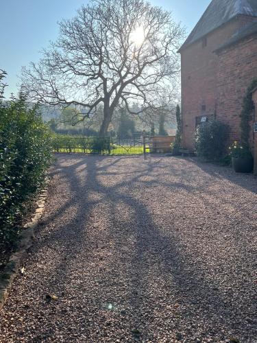 a shadow of a tree on the ground next to a building at Pet Friendly Manor House Hop Kiln in Ledbury