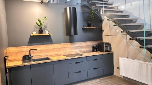 a kitchen with a counter with a sink and a staircase at APARTAMENT LUX Bulwary Chrobrego Gniezno in Gniezno