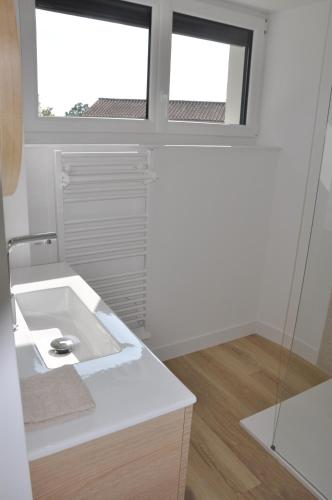 a white bathroom with a sink and two windows at 285 - gite de la rue du Chateau Aizenay in Aizenay