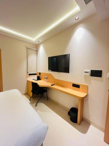 a bedroom with a desk with a television on the wall at Nirvana Nest in Lucknow