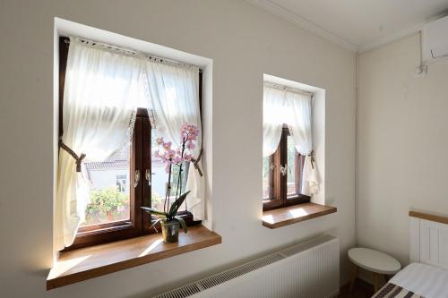 a bathroom with two windows with a plant in a vase at OneLife Retreat 