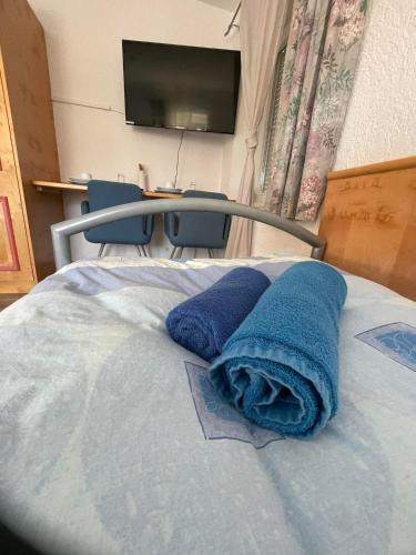 a bed with two blue towels on it with a television at ZV-Scholtz Gästehaus Neuötting Simbacher Straße 7 in Neuötting