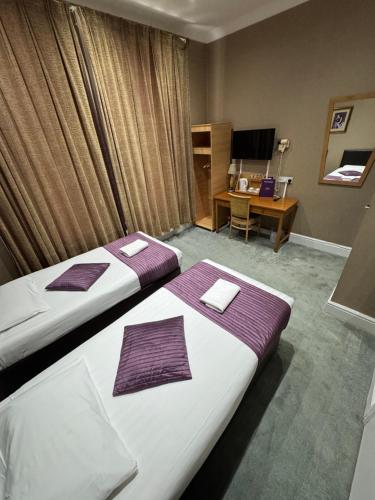 a hotel room with two beds and a desk at Newham Hotel in London