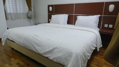 a large bed with white sheets and pillows at Diyar Villas Puncak M6/14 in Puncak