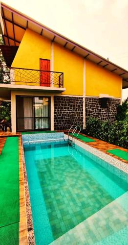 a swimming pool in front of a house at Enliven Homestay Alibag, Alibaug in Nagaon