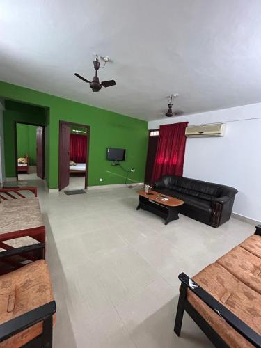 a living room with green walls and a black couch at Sreenidhi Apartment Guruvayoor in Guruvāyūr