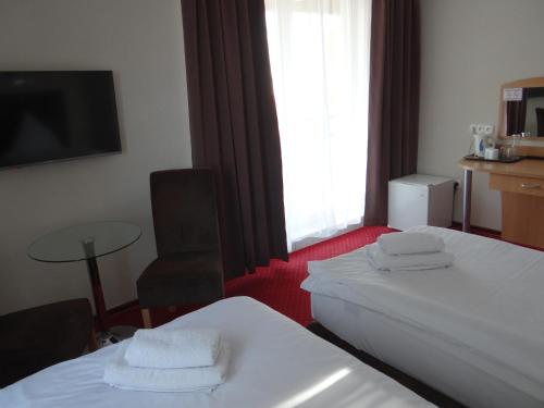 a hotel room with two beds and a table and a window at Hotel Relax in Słubice