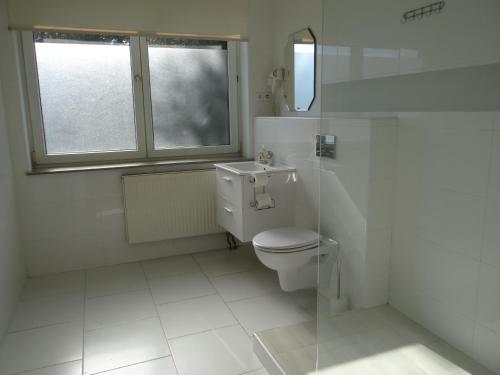 a white bathroom with a toilet and a window at Hotel Relax in Słubice