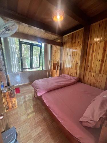 a large bed in a room with wooden walls at Mộc Thiên Xanh homestay in Kon Plong