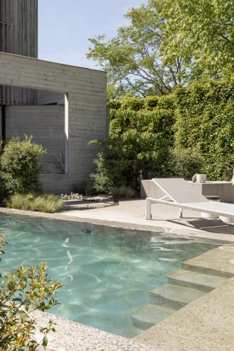 a swimming pool with a bench next to a house at Tranquil Designer Stay with Infinity Pool in Merchtem