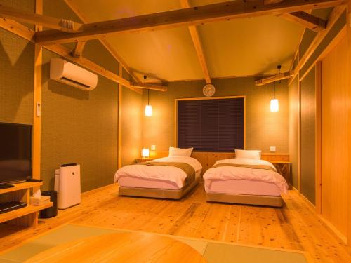 two beds in a room with a tv and a room with at Isaribinoyado Seaside Kancho in Wakayama