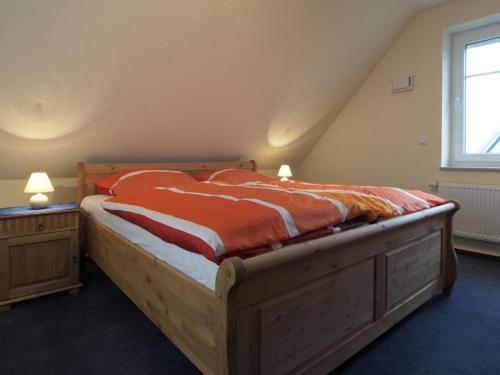 a bedroom with a wooden bed with an orange comforter at Schneckenhaus Ferienhaus in Groß Schwansee