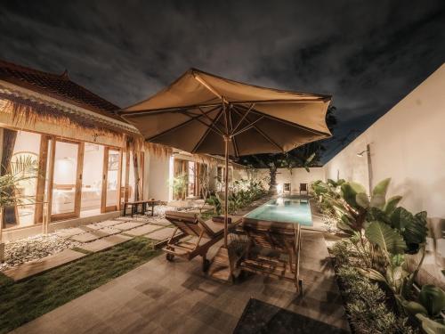 a patio with an umbrella and a swimming pool at Hiraya Uluwatu in Uluwatu