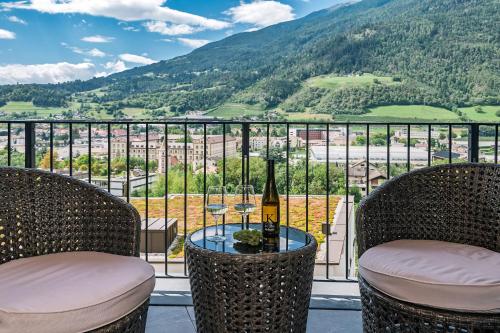 a balcony with a table with wine glasses and a view at Knöspele - Brennerei & Genuss-Apartments in Brixen