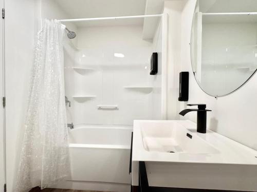 a white bathroom with a sink and a mirror at Levis Downtown New Studio #3 AC, WiFi and 2 Parking spaces in Lévis