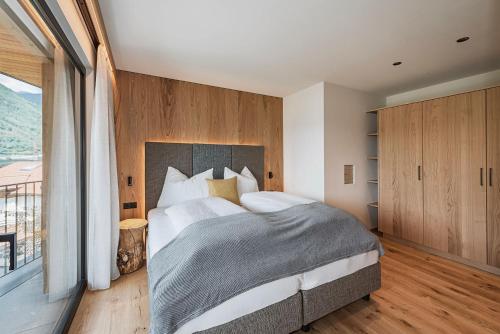 a bedroom with a large bed and a balcony at Knöspele - Brennerei & Genuss-Apartments in Brixen