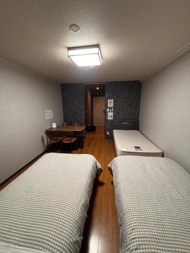 a room with two beds and a table in it at BEPPU HOSTEL U&T in Beppu