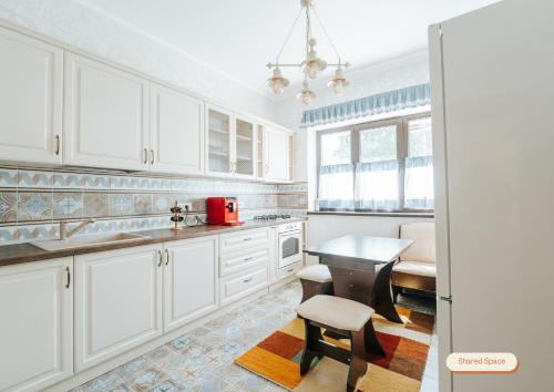 a kitchen with white cabinets and a table and stool at Vila Anisoara in Predeal