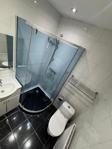 a bathroom with a shower with a toilet and a sink at Newham Hotel in London