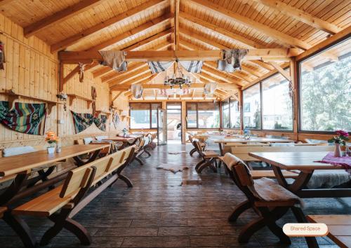 a dining room with wooden tables and benches and windows at Vila Anisoara in Predeal