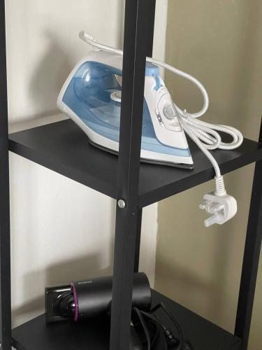 a black shelf with a iron and a phone on it at MKB Homestay - 2 X Queen Bed Studio Room with View and Free Parking in Klang