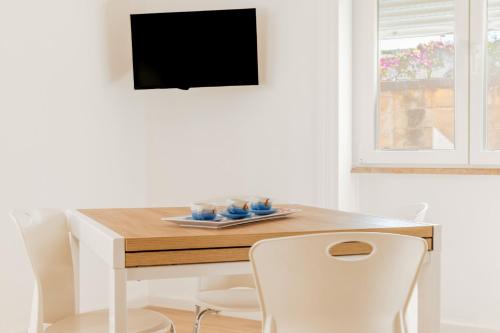 a dining room table with white chairs and a television at Micenei Homes in Otranto