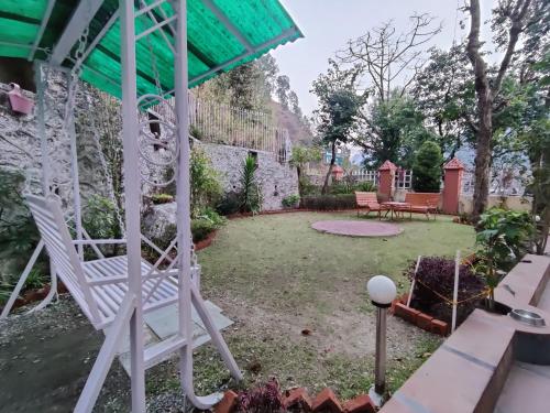 a garden with a white rocking chair in a yard at DreamCatcher By Samyati Hotels and Resorts in Bhīm Tāl