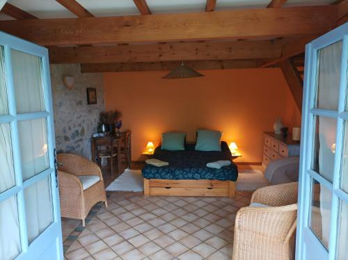 a bedroom with a bed and two wicker chairs at Campagne de Pré Grand in Saint-Étienne-les-Orgues