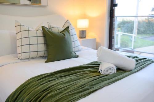 a bed with a green blanket and a laptop on it at Stunning 4BR Home with Pool & Water Views in Koolewong