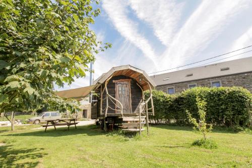 a small tree house in a yard with a bench at La Roulotte de Menugoutte in Herbeumont