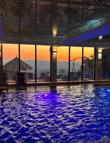 a swimming pool in a building with a sunset in the background at Snow peak Wellness & Spa, Kopaonik Milmari N5 in Kopaonik