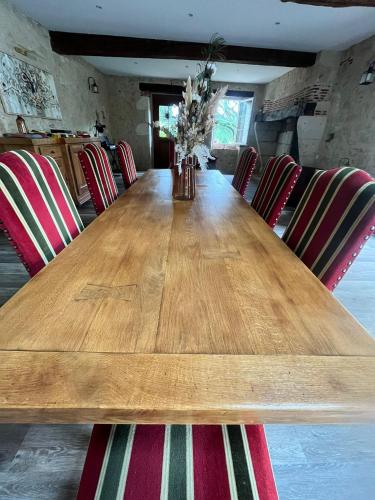 a long wooden table with red and green chairs at Domaine de Pourrouquet - Demeure de charme et Gîte in Vic-Fezensac