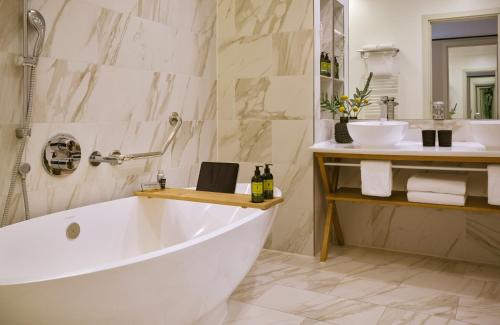 a white bath tub in a bathroom with a sink at The Posthouse Berlin Potsdamer Platz- Leonardo Limited Edition in Berlin