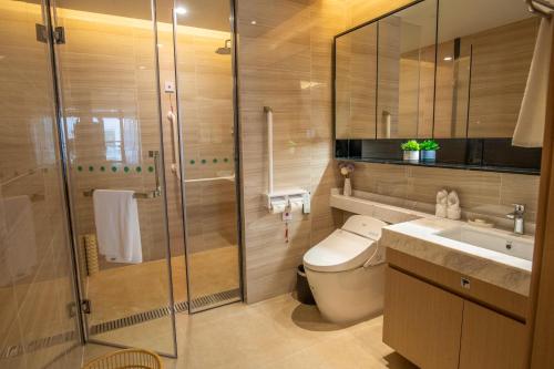 a bathroom with a shower and a toilet and a sink at Sanya Haitang Bay Health Valley Resort Hotel in Sanya