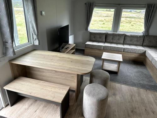 a living room with a table and a couch at Luxury static caravan on SunnySands with mountain views in Barmouth